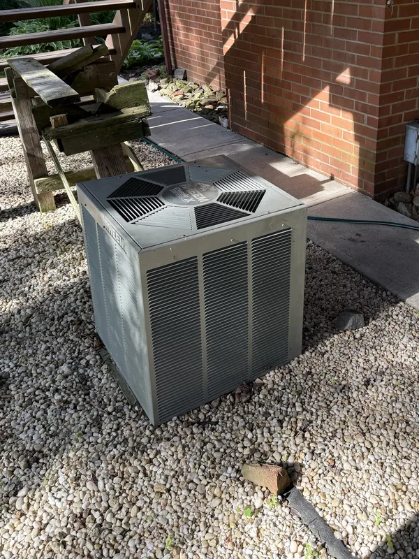 Outdoor AC unit on a gravel pad beside a brick house during an AC tune-up in Olmsted Falls, OH