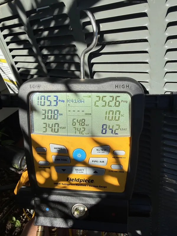 Refrigerant gauge hung on the outdoor AC unit, showing system pressures during an AC tune-up in Rocky River, OH