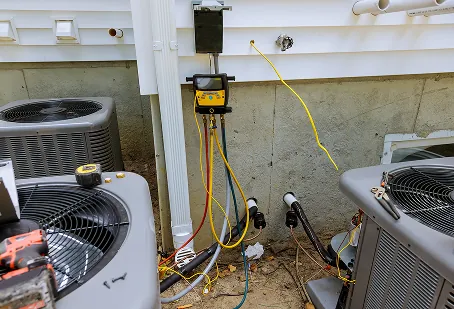 Refrigerant gauges hooked up to two outdoor AC units during a service check