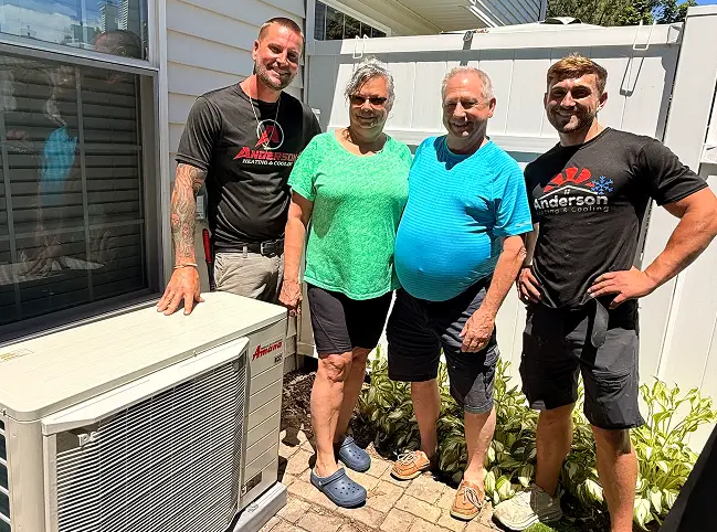 Two Anderson technicians and the homeowners beside a new Amana mini-split outdoor unit