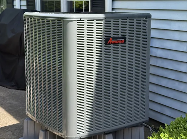 New Amana air conditioner condenser installed beside a home