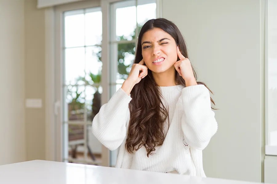 Woman with her fingers in her ears, wincing