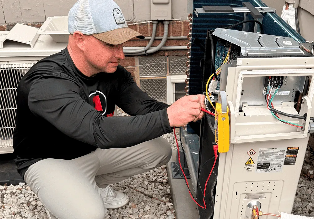 Technician checking the wiring of an outdoor unit with a clamp meter