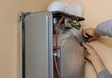 Technician’s hands working inside a wall-mounted gas boiler with its cover open