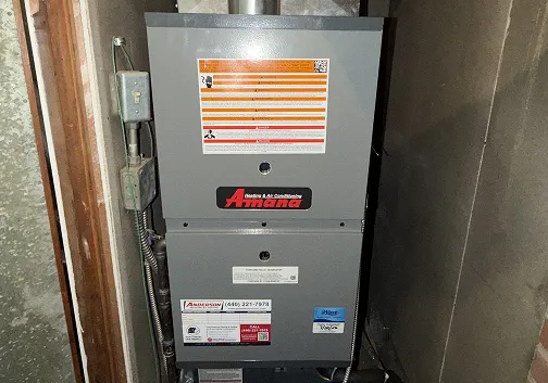 Amana furnace in a basement with an Anderson Heating & Cooling sticker on the front