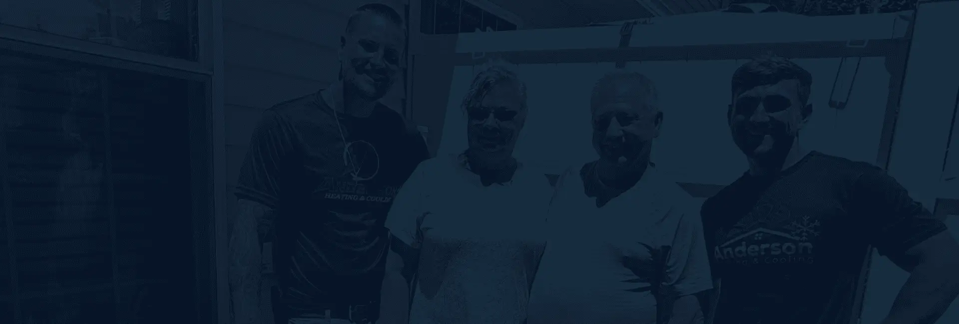 Two Anderson technicians standing with two homeowners outside a home