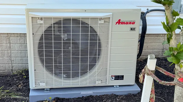 New Amana mini-split outdoor unit on a pad beside a house