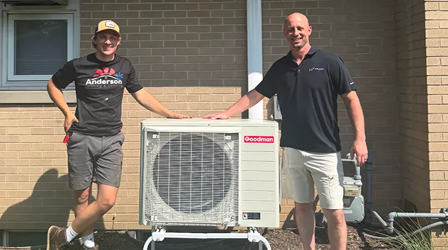Anderson technician and another man standing beside a new Goodman mini-split outdoor unit